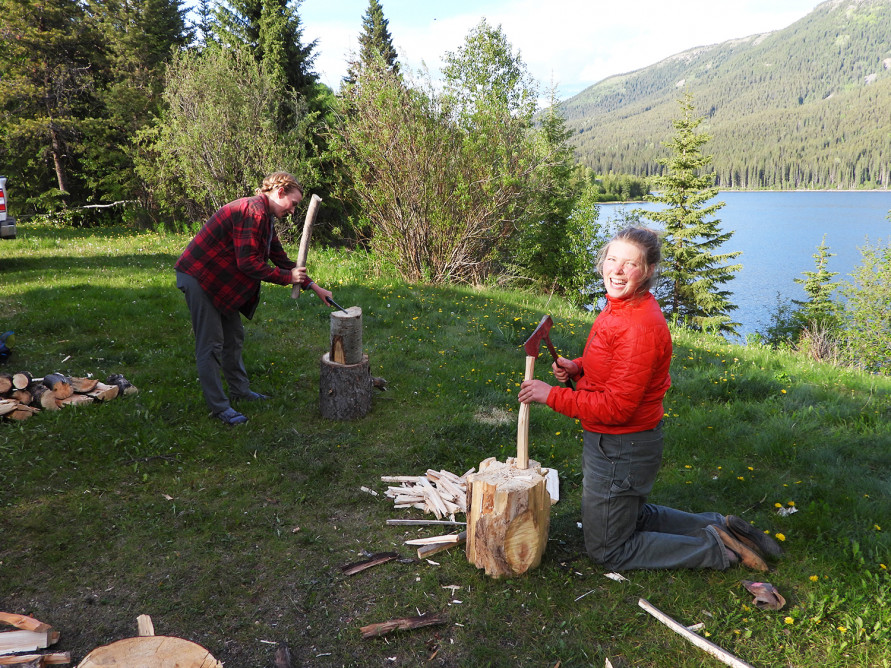 Janine and Nikki chopping firewood beside a lake