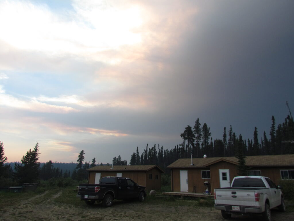 a cabin and trucks with a smoky sky