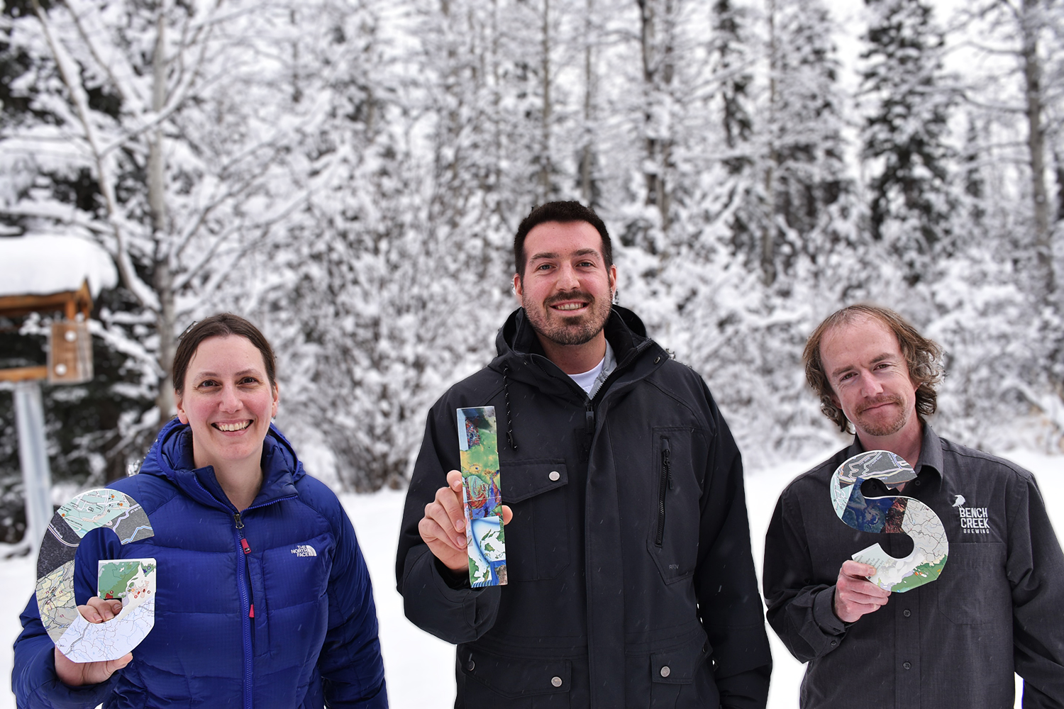 Julie Duval Dan Wismer Josh Crow stand in a snowy area holding wood block letters that say GIS