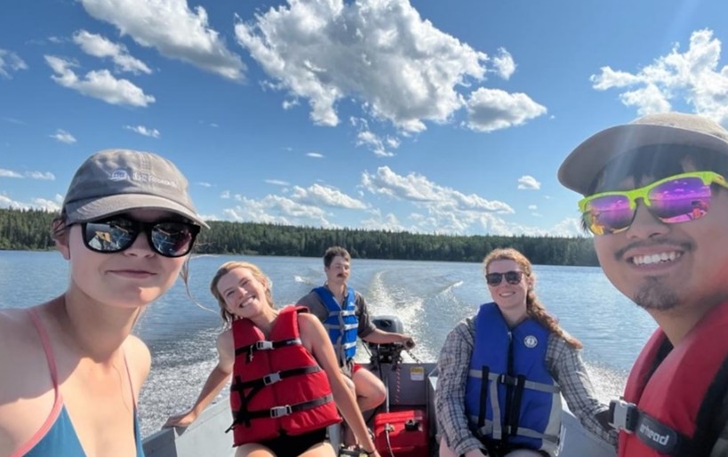 smiling field crew in a boat on a lake
