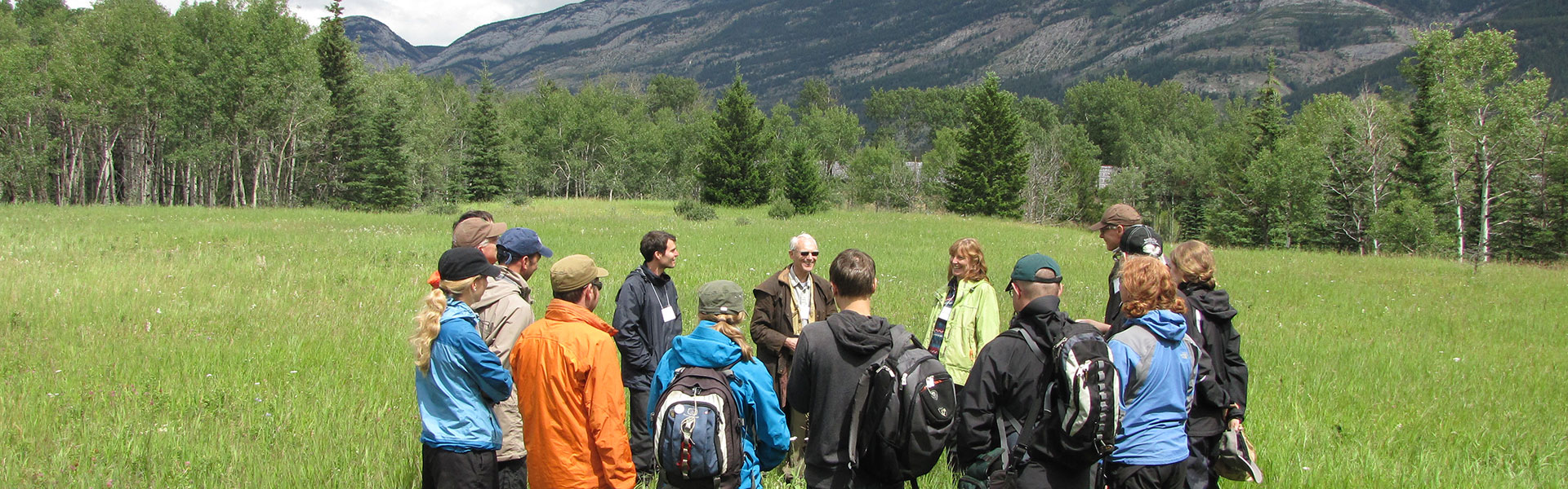 group of people standing in a circle in a mountain meadow