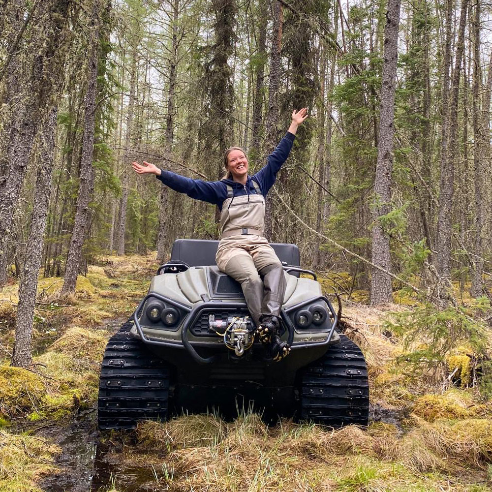 Madison sitting on an Argo OHV, parked at a somewhat muddy section of road.
