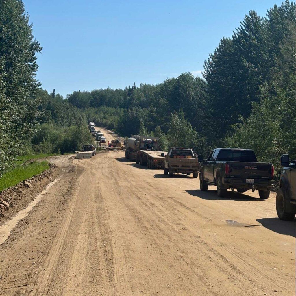 a lineup of trucks on a gravel road through the forest, stopped for road construction pc javier puac
