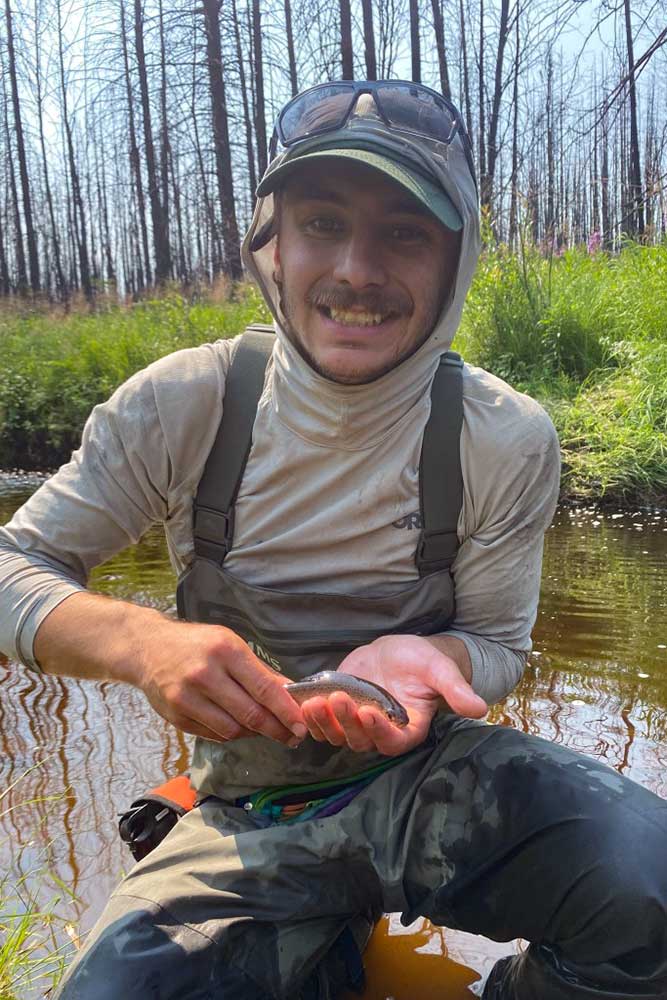 jesse holds an arctic grayling in a stream. 