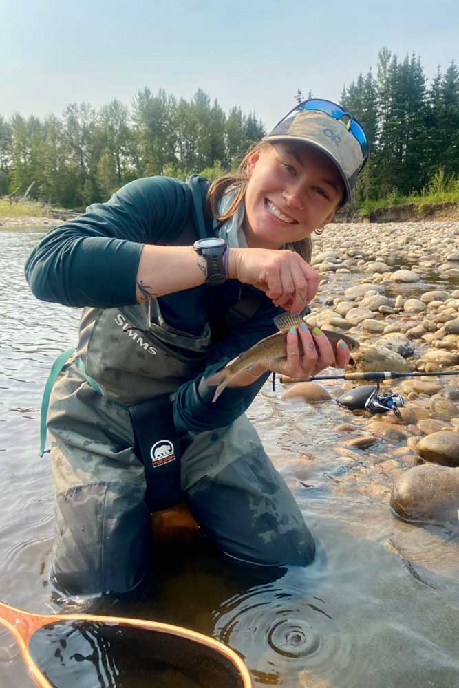 sarah holds an arctic grayling in a stream. 